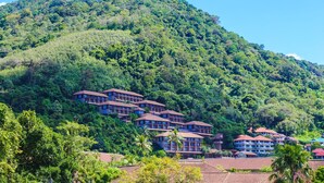 Un complejo turístico con varias edificaciones en una ladera, rodeado de exuberante vegetación.
