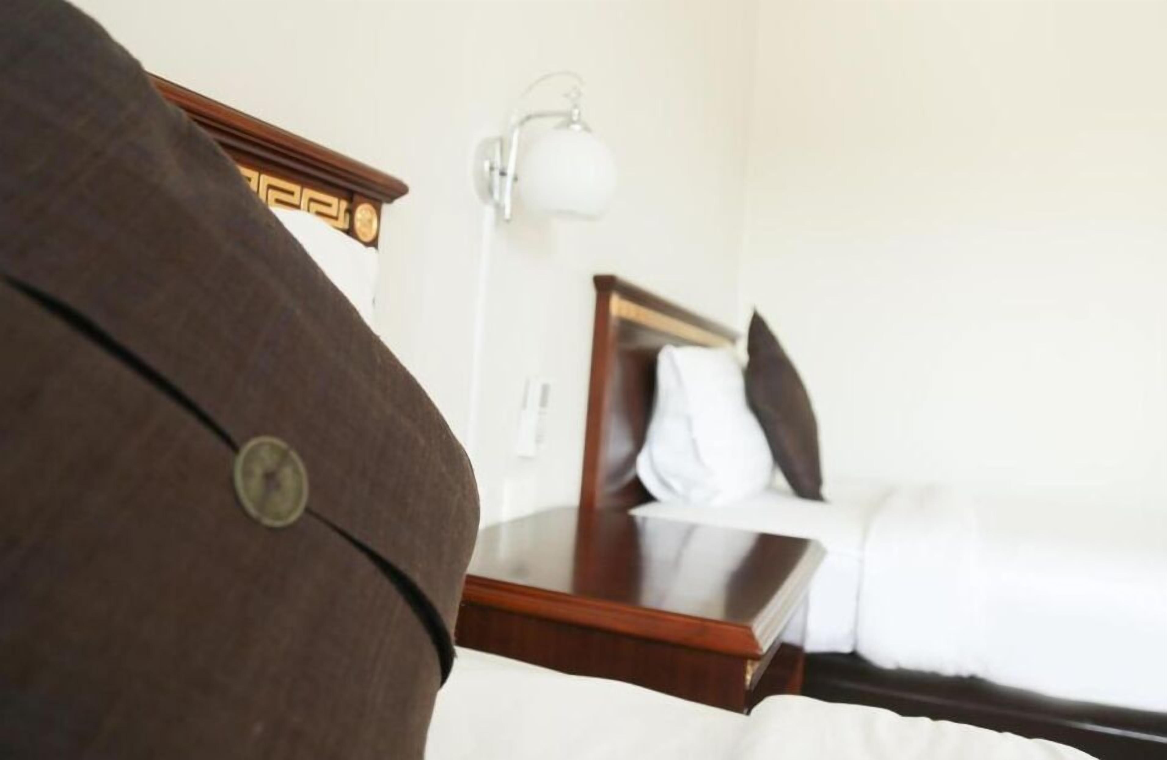 A hotel room with a bed, a bedside table, a lamp, and a wooden headboard.