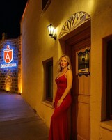 Mulher de vestido vermelho em frente a um edifício com uma placa que diz 'Lobby'.