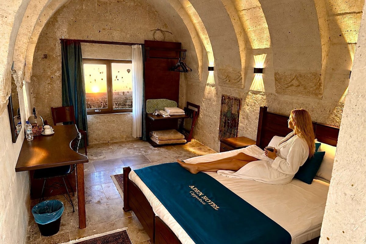 Quarto com cama, escrivaninha, cadeira, janela e vista para o exterior.