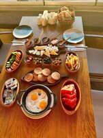 A wooden table with various food items including eggs, cheese, bread, and fruits.