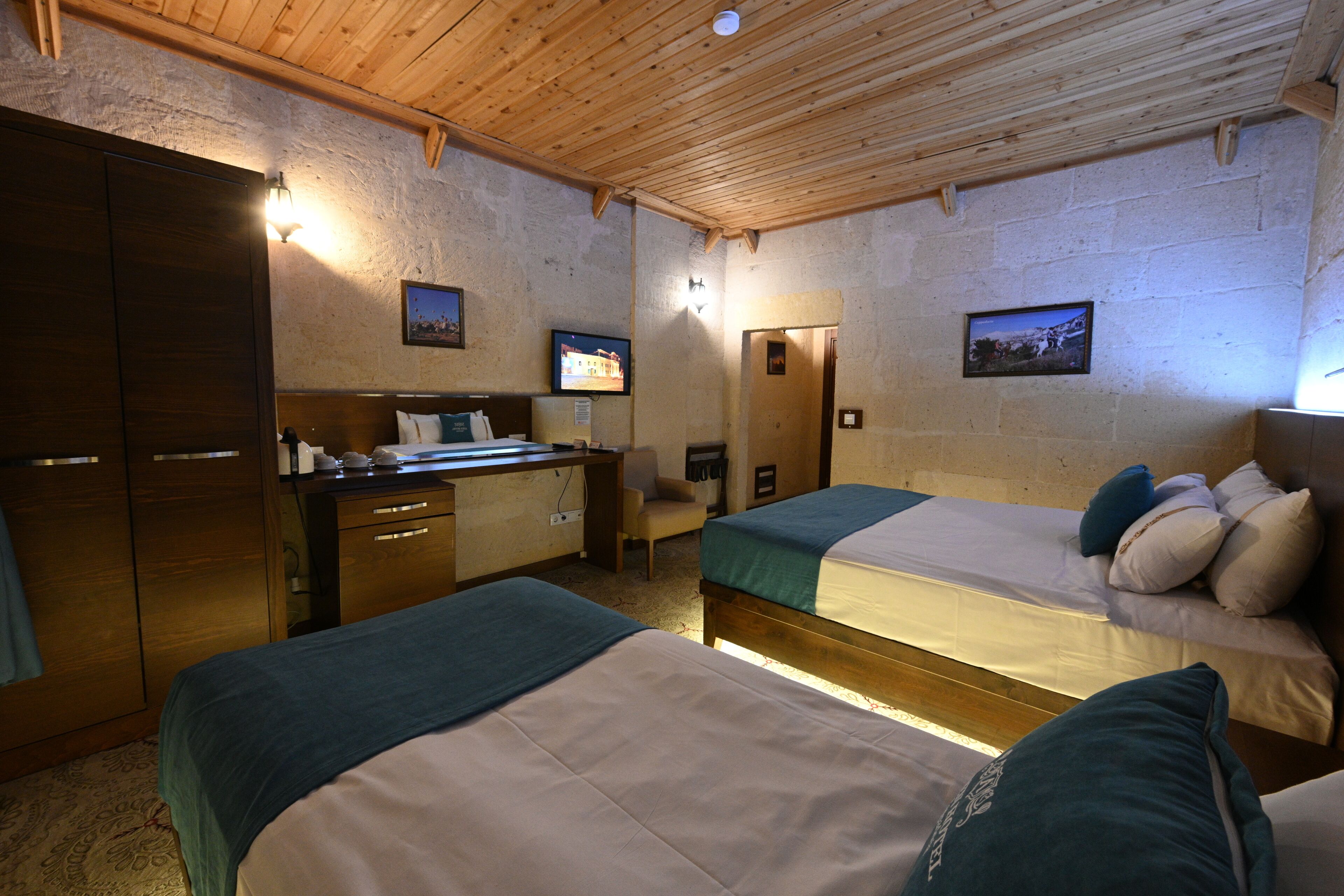 Una habitación con dos camas, un escritorio, una silla y una televisión.