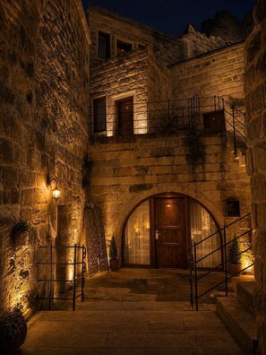 Un edificio de piedra con puerta de madera, una escalera y un farol.