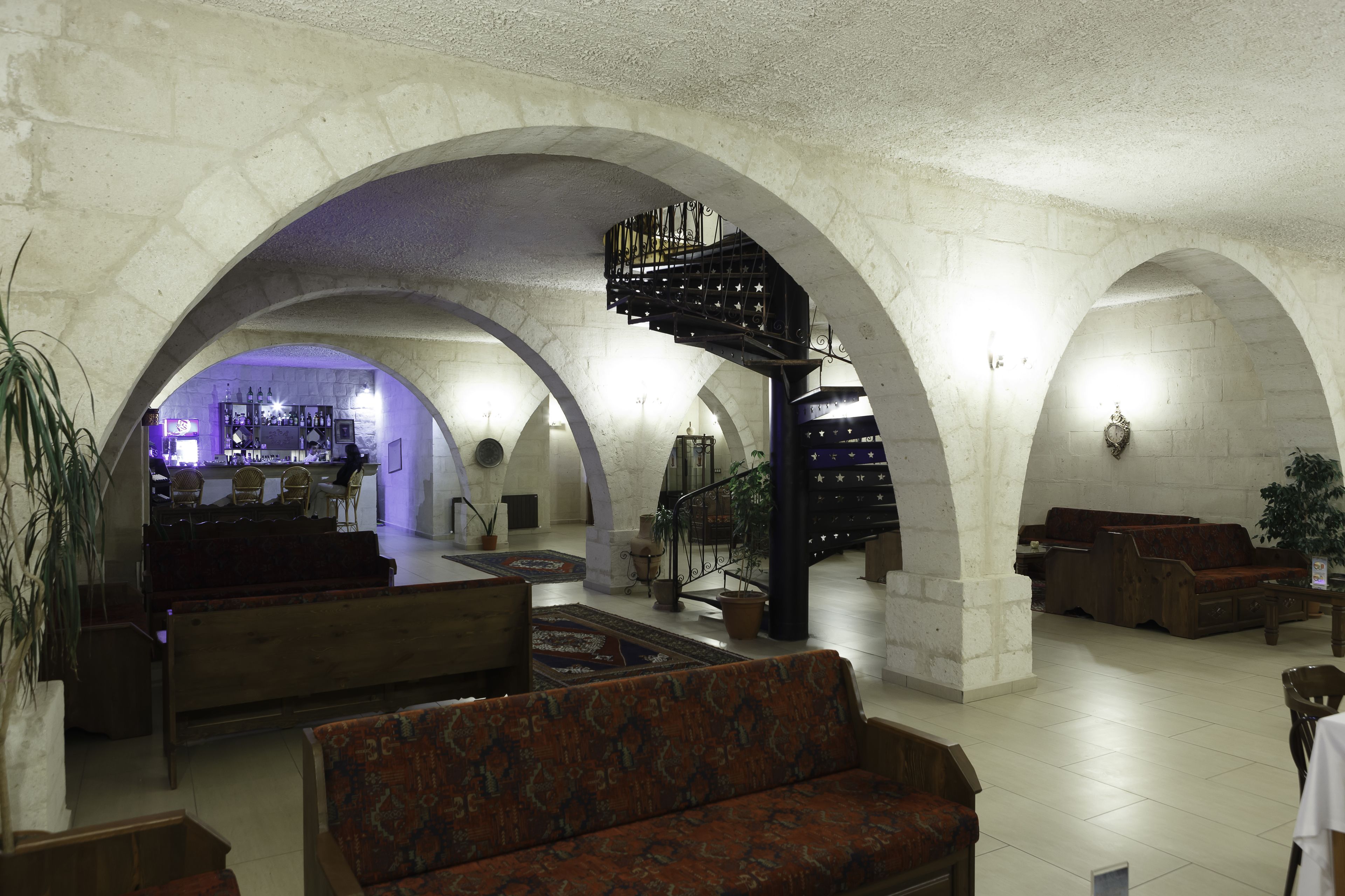Un amplio vestíbulo con una escalera central, zonas de estar y un bar al fondo.