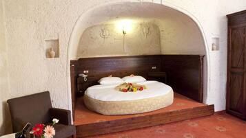 Un dormitorio con cabecera de madera, cama con ropa blanca, mesita de noche y una silla.