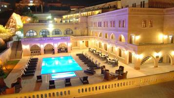 Un patio de hotel con piscina, tumbonas y una escalera que sube a los pisos superiores.