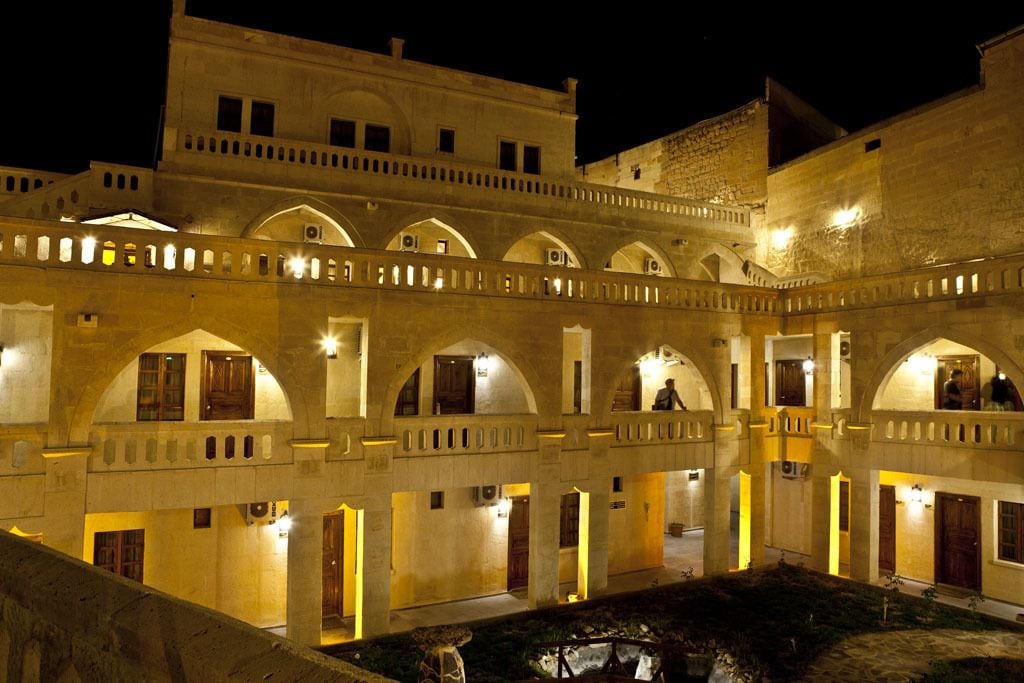 A historic building with multiple arched corridors and balconies, illuminated by warm lighting.