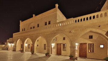 Um edifício histórico com arcadas e várias portas, provavelmente um hotel ou edifício público.