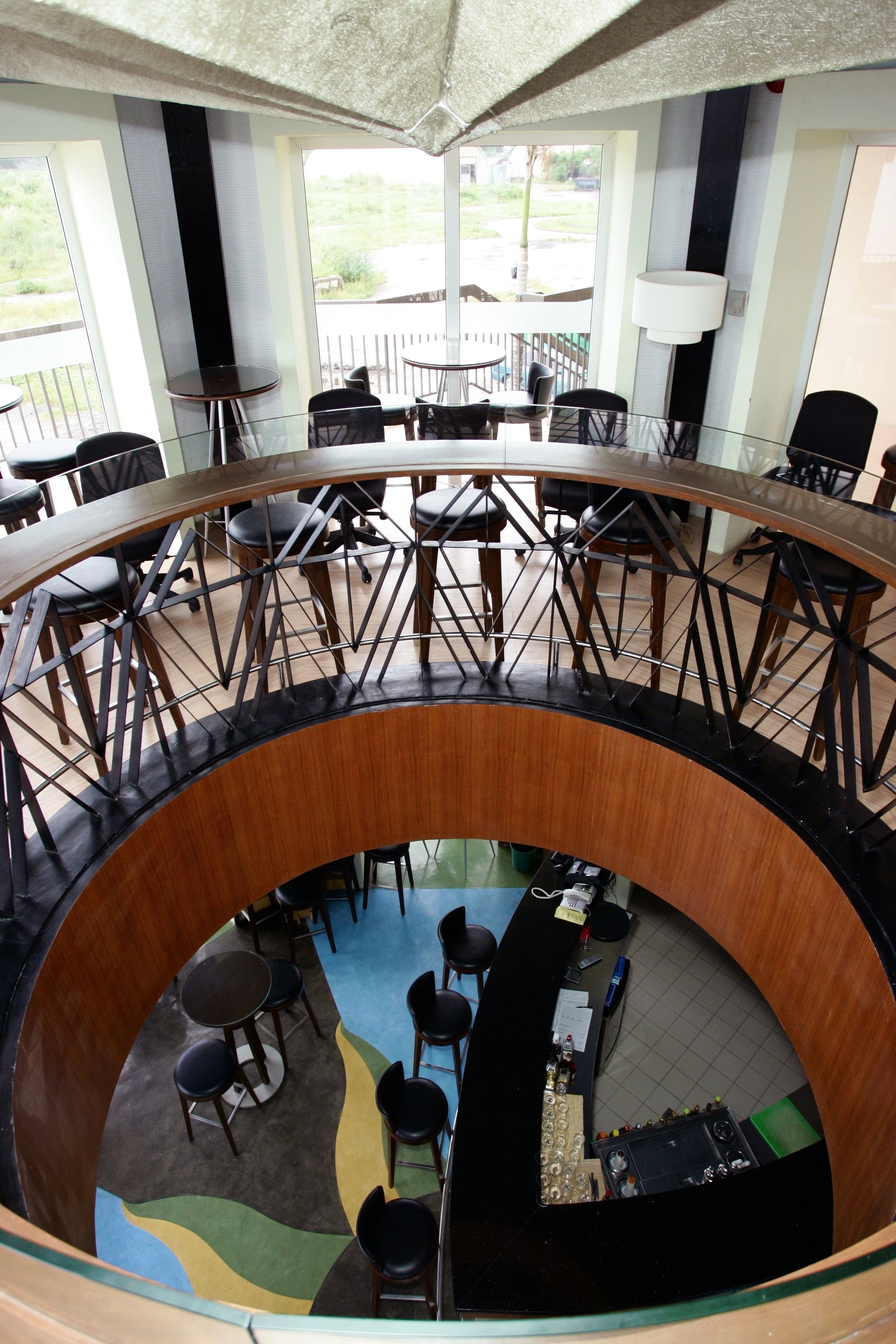 A circular interior with a central bar area, multiple seating arrangements, and a view of the outdoors through large windows.
