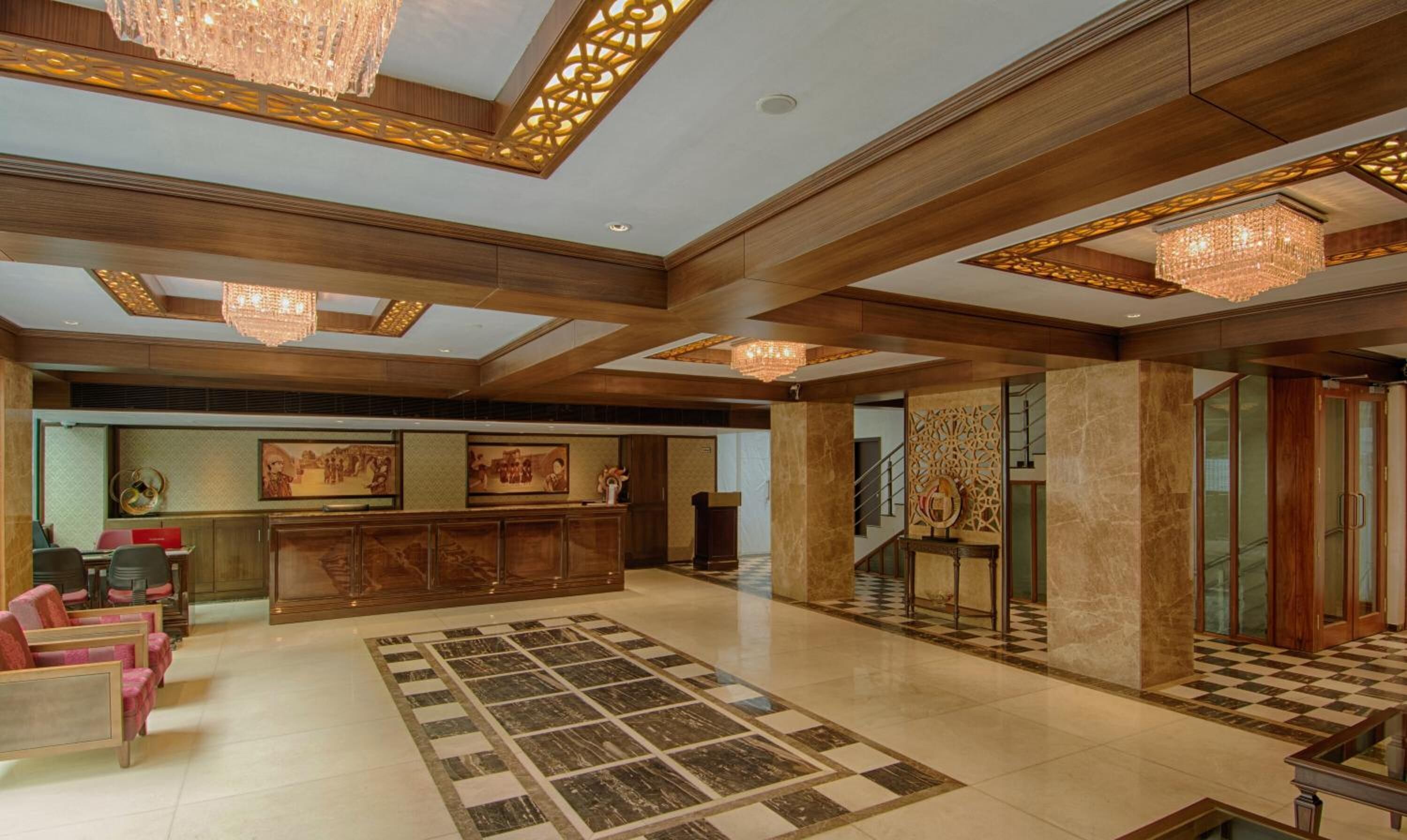 Un hall d’entrée spacieux, doté d’un sol à carreaux, de boiseries et de plusieurs lustres.