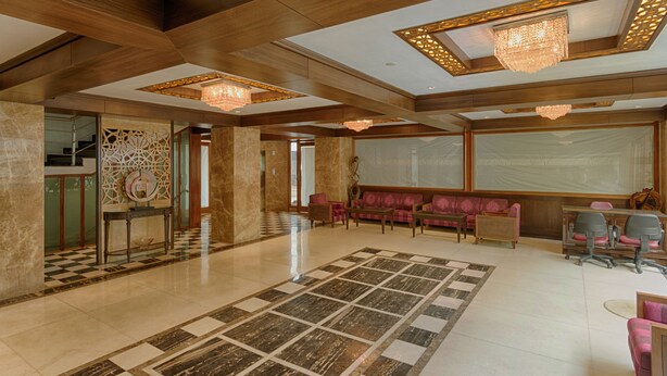 A spacious lobby with a checkered floor, a seating area with sofas, and a reception desk.