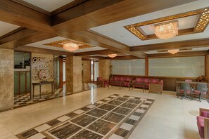 A spacious lobby with a checkered floor, a seating area with sofas, and a reception desk. - The President - A Boutique Hotel (Ahmedabad)