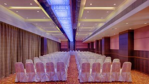 A conference room with rows of chairs, a patterned carpet, and a modern ceiling design.