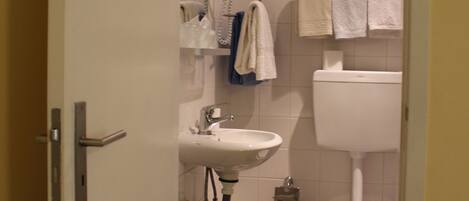 Un baño con lavamanos, inodoro y toallero.