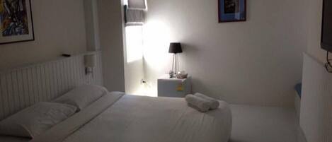 A hotel room with a bed, a nightstand, a lamp, and a wall-mounted TV.