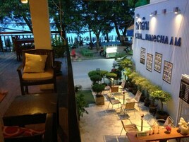 Un restaurante con terraza, que incluye sillas y mesas de madera, rodeado de plantas en macetas.