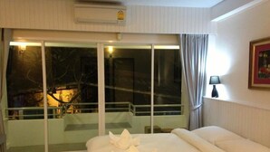 Een hotelkamer met een groot bed, een balkon met een glazen deur en een uitzicht op de nacht.