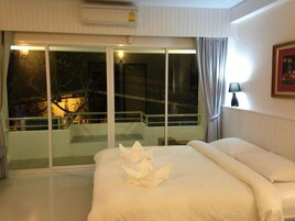Una habitación de hotel con una cama grande, un balcón con puerta de cristal y vistas nocturnas.