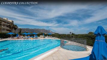 Piscine couverte, piscine extérieure, parasols de plage, chaises longues