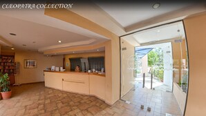 A reception area with a counter, a bookshelf, and a potted plant. - Cleopatra Superior (Kos)