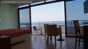 A hotel room with a bed, a desk, and a balcony with a view of the sea. - Cleopatra Superior (Kos)