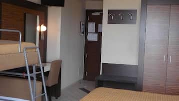 A room with bunk beds, a desk, a chair, a wardrobe, and a TV.