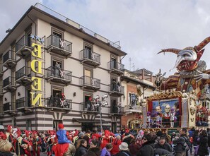 A building with multiple balconies and a large, colorful float with masks and figures. - Hotel Eden (Viareggio)