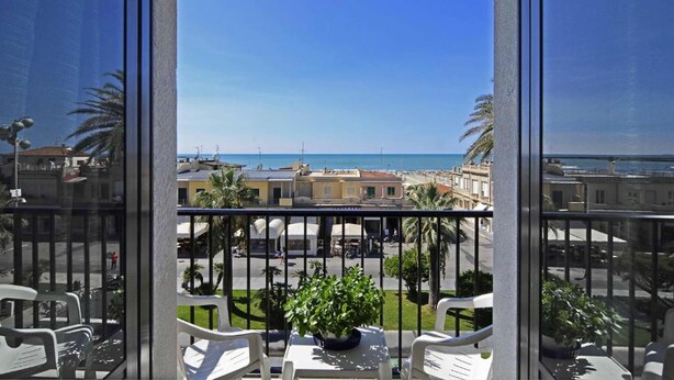 A balcony with a view of the sea and cityscape. - Hotel Eden (Viareggio)