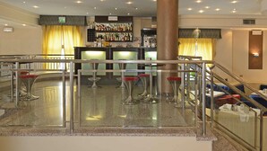 A bar area with a counter, stools, and a staircase leading to a seating area. - Hotel Eden (Viareggio)