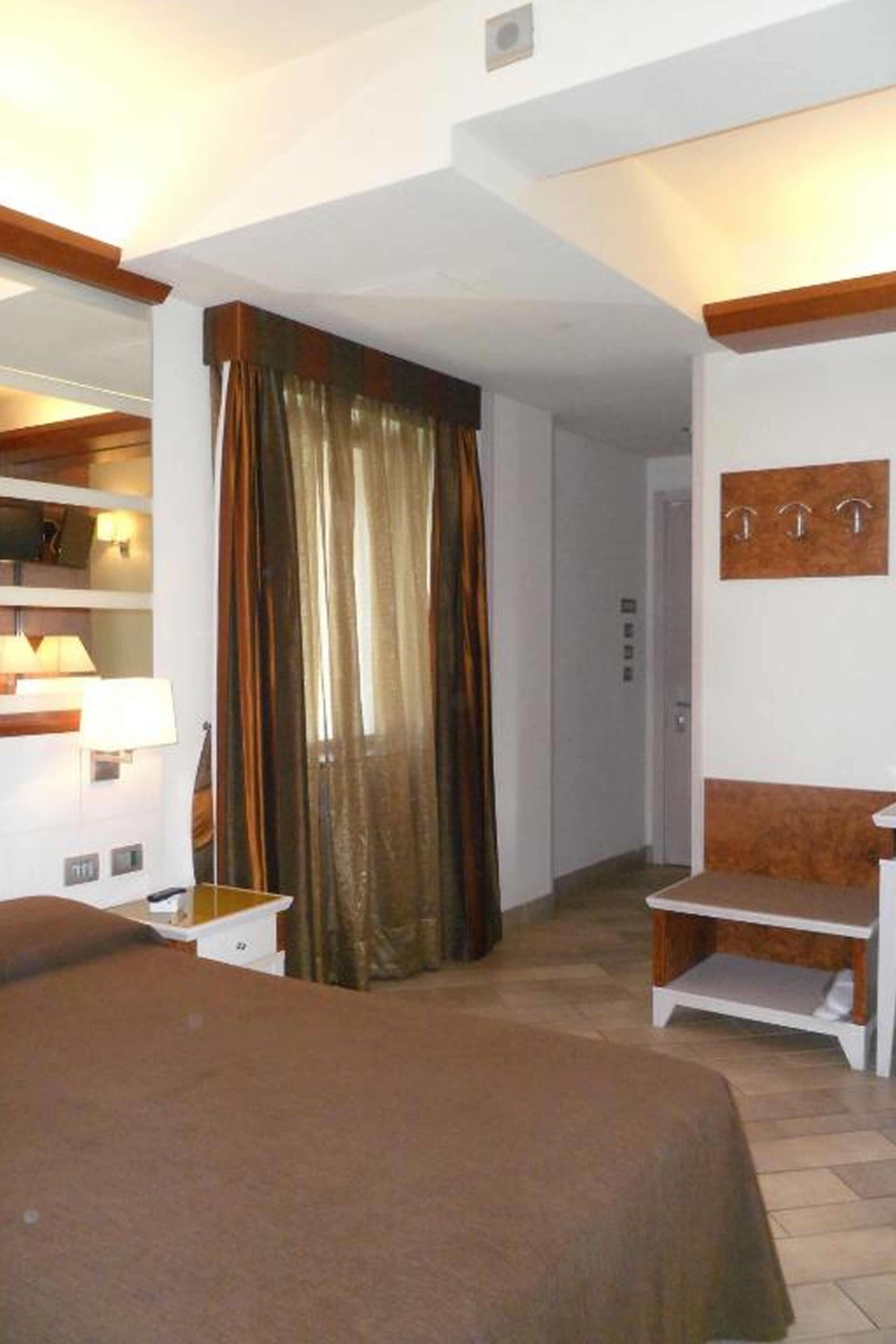 Et hotelværelse med seng, sengebord, lampe og et spejl.