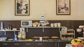 Ein Frühstücksbuffet mit verschiedenen Speisen, einer Mikrowelle und Dekoration auf der Theke.