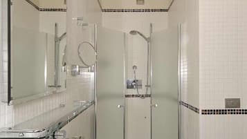 Un baño con un lavabo blanco, un espejo, una ducha con puerta de vidrio y un techo con diseño perforado.