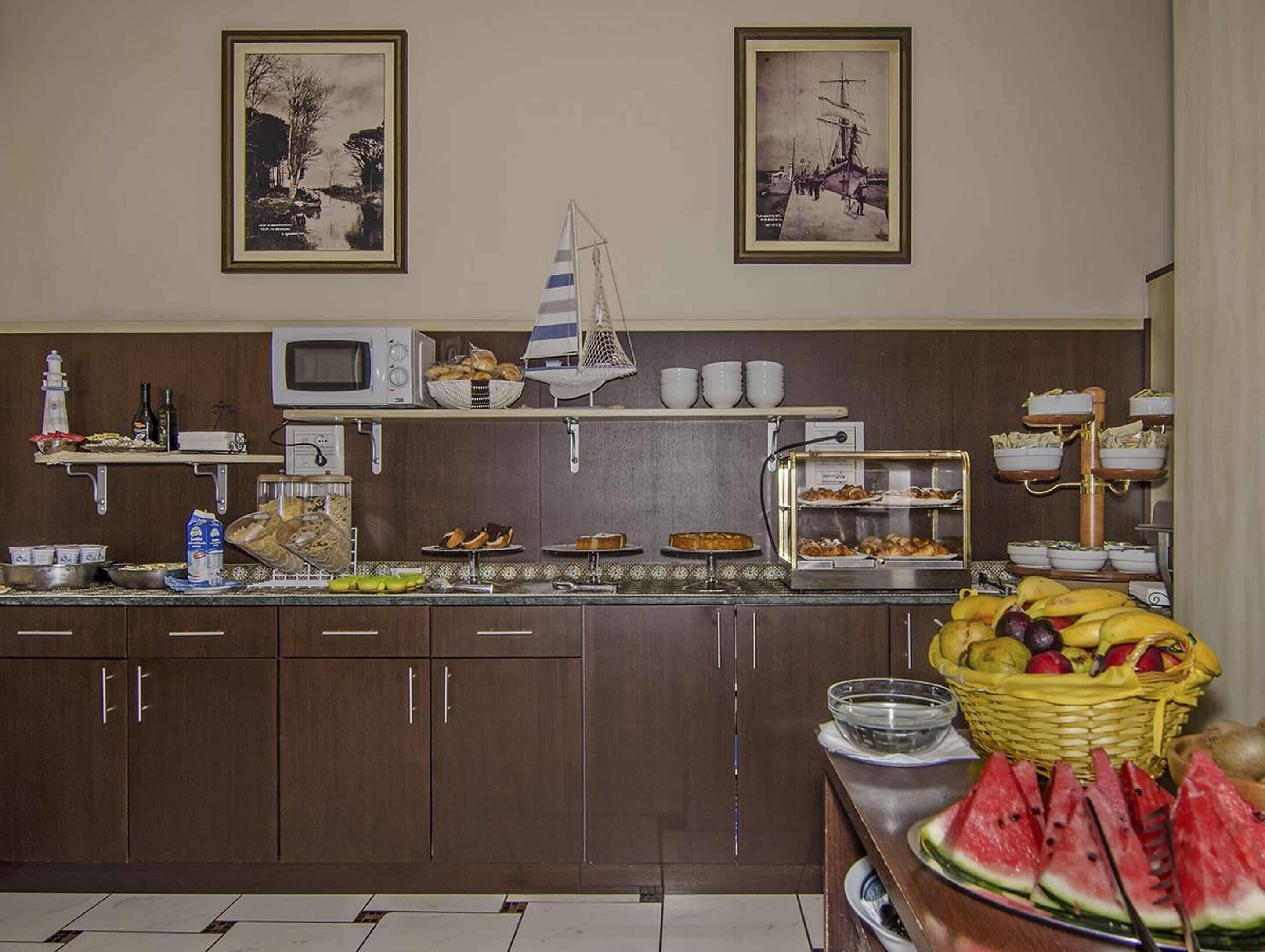 A kitchen with a microwave, various food items, and two framed pictures on the wall.