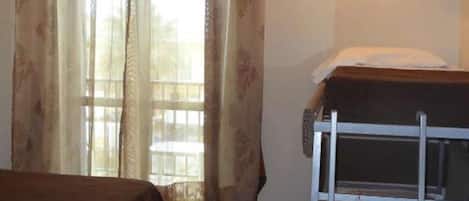 A room with a bed, a desk, and a window with curtains.