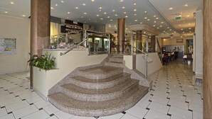 A hotel lobby with a central staircase, a bar area, and a seating area. - Hotel Eden (Viareggio)