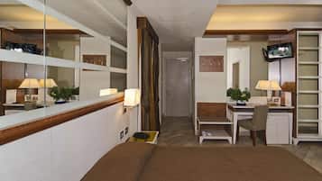 Ein Hotelzimmer mit Schreibtisch, Stuhl und Fernseher an der Wand.