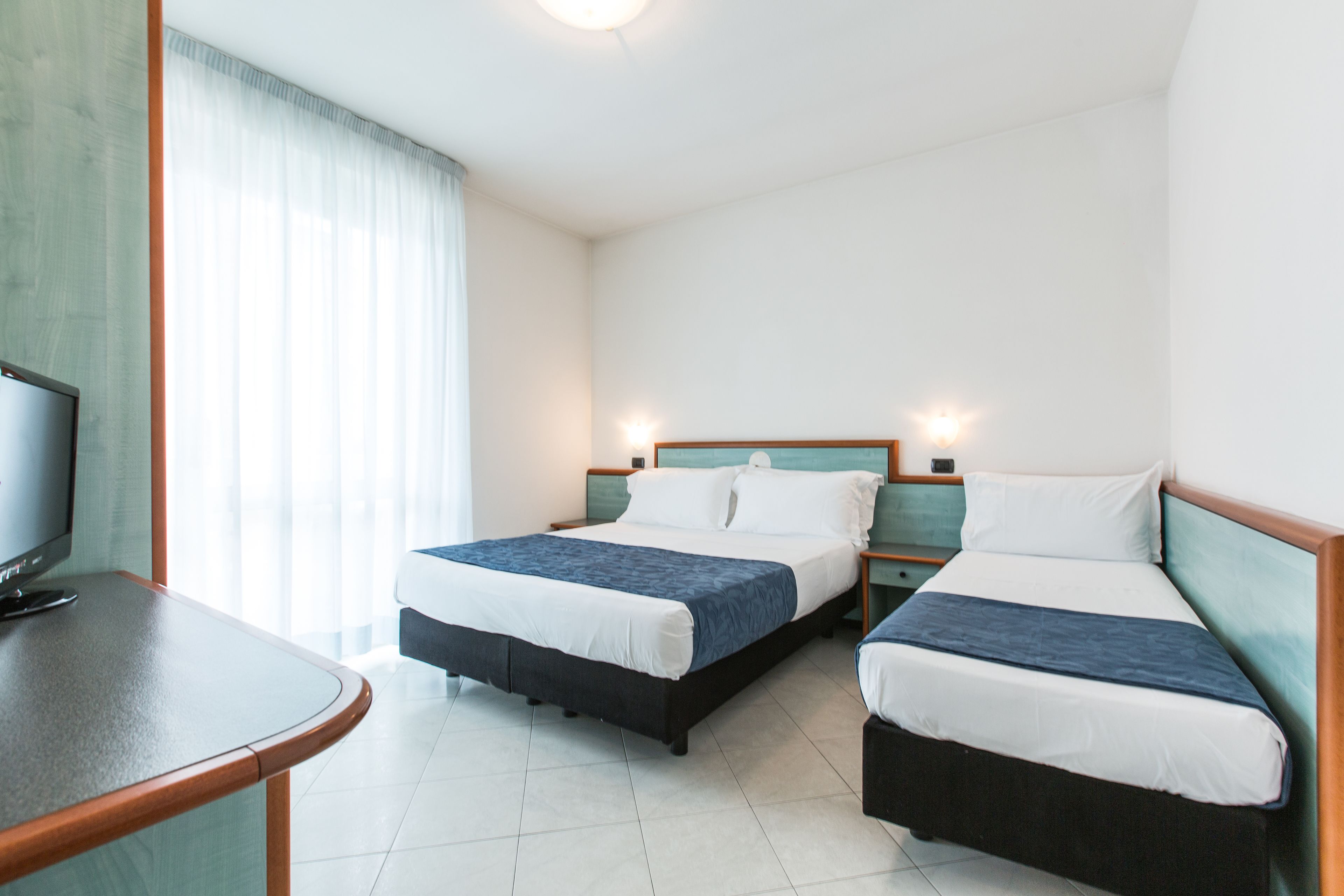 Une chambre d’hôtel avec deux lits, une télévision et un bureau.
