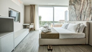 Una habitación de hotel moderna con una cama grande, un escritorio y un televisor.
