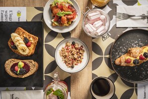 A table with breakfast items including toast with berries, a salad, granola, and a croissant. - Hotel Luxor (Cervia)