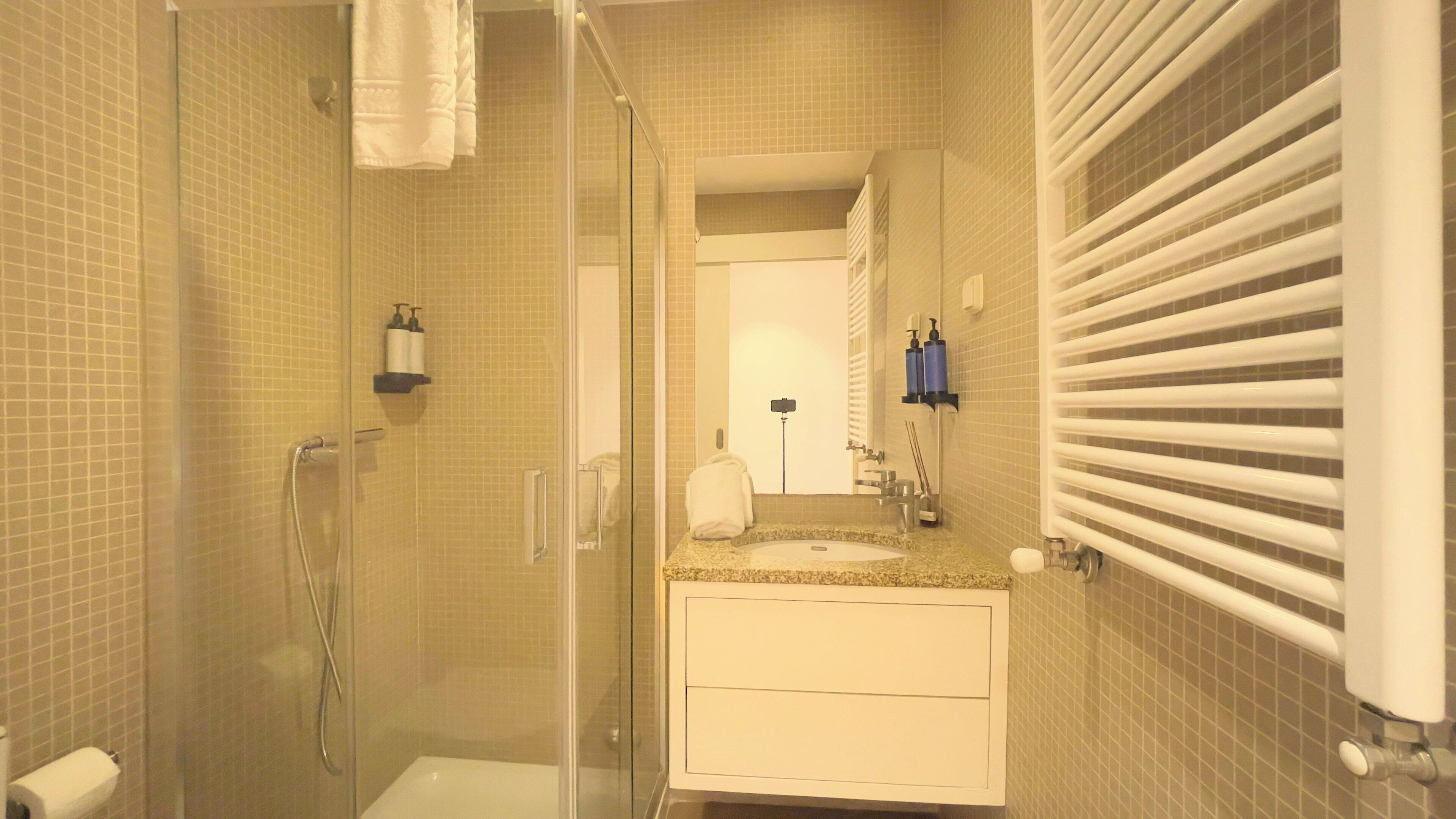 Une salle de bain moderne avec une douche à parois de verre, un lavabo avec un miroir et un porte-serviettes.