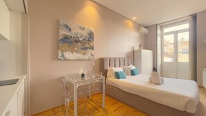 Een hotelkamer met een bed, een klein tafeltje met stoelen, een schilderij aan de muur en een kledingkast.
