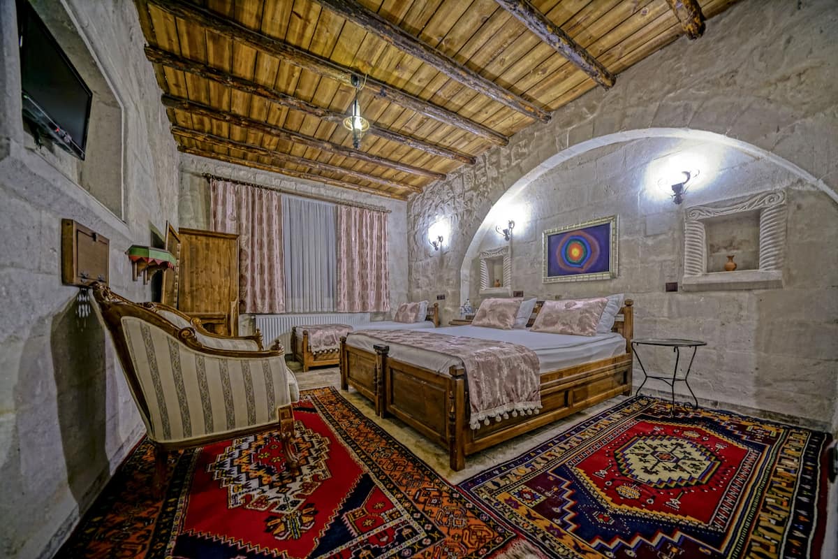 A traditional room with a wooden bed, a chair, and a patterned rug.