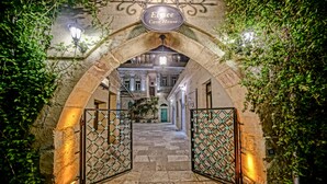 An entrance to Elysee Cave House with an arched stone gateway, a sign above, and a pathway leading to a building. - Elysée Cave House (Nevsehir)