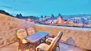 A terrace with wicker furniture overlooking a town with unique rock formations and traditional buildings. - Elysée Cave House (Nevsehir)
