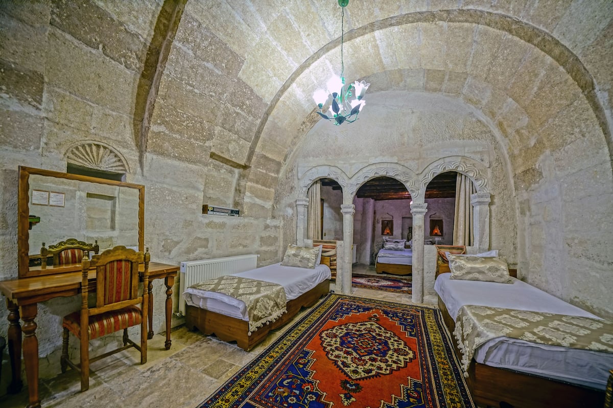 A room with two beds, a wooden desk, a mirror, and a patterned rug.