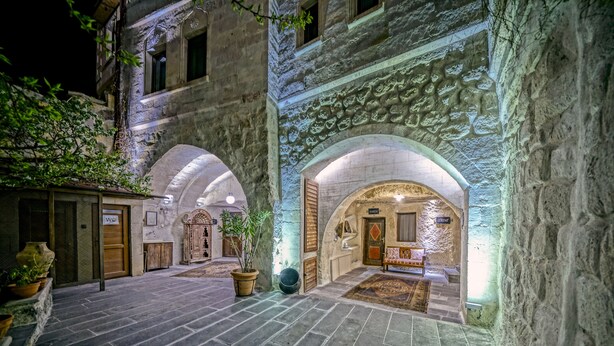 A historic building with stone arches, a reception area with a bench, and a sign indicating a WC. - Elysée Cave House (Nevsehir)