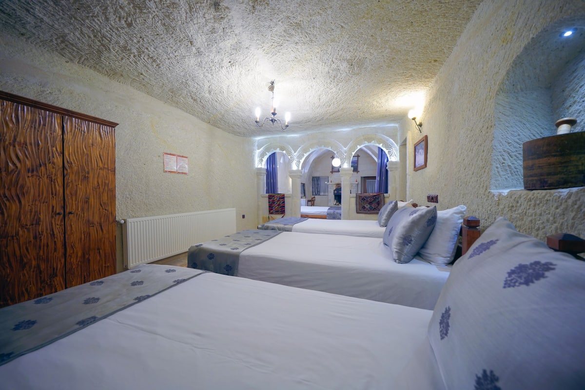 A room with two beds, a wooden wardrobe, and a mirror.