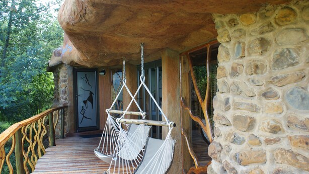 A stone building with a wooden deck and a hammock chair.