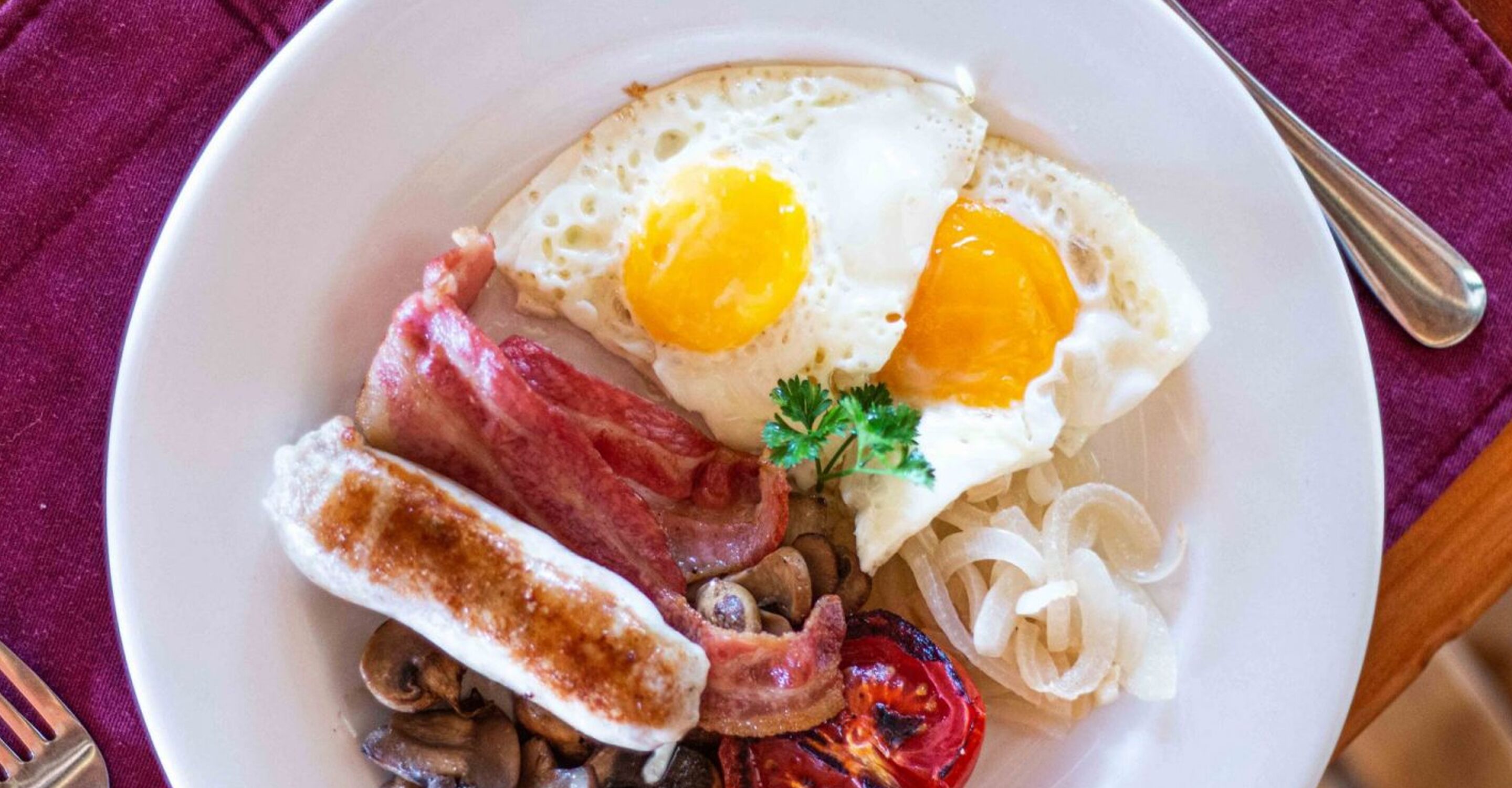 A plate of breakfast with eggs, bacon, mushrooms, and grilled tomatoes.