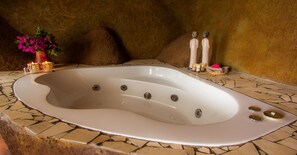 Une baignoire de spa avec un sol en mosaïque, un vase rempli de fleurs et deux bouteilles décoratives.